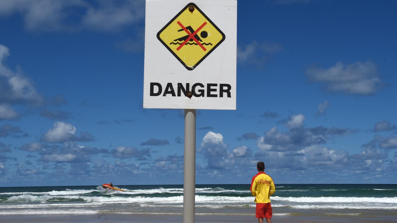 A surf rescue boat, lifesaver and swimmer warning sign