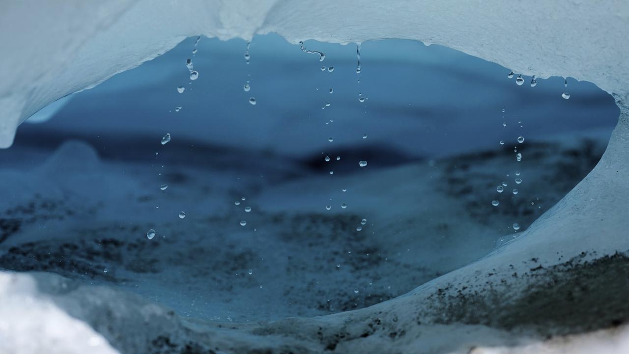Water drips from a melting chunk of ice on a glacier