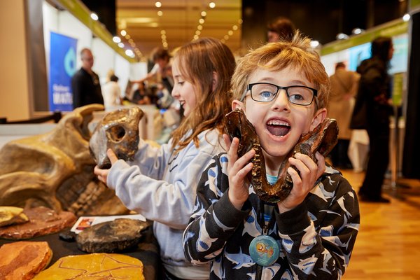 Two excited children handle fossil specimens at a stall at the Sydney Science Trail Community Day