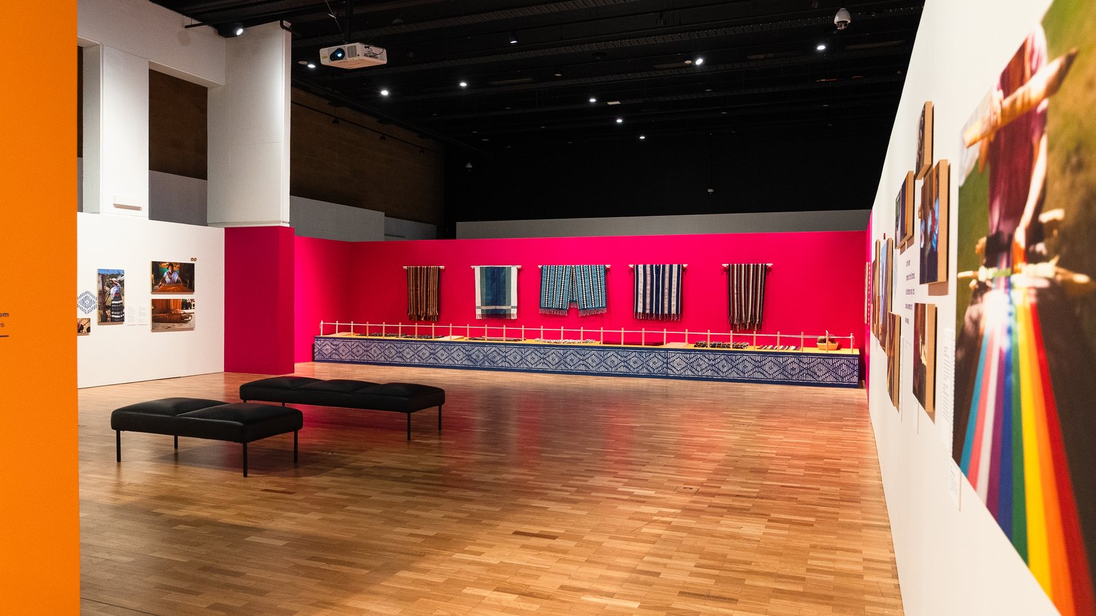 Gallery view of Mexican textiles and art exhibition, featuring woven works and photographic displays