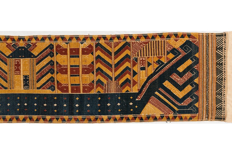 Ceremonial textile (Palepai) featuring geometric patterns in gold, navy, and red on a cream ground.