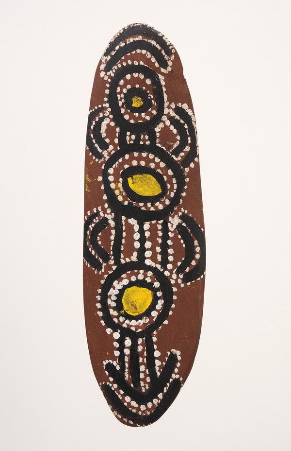 An oval wooden dance board painted with concentric circles, dot patterns and yellow ovals in black.