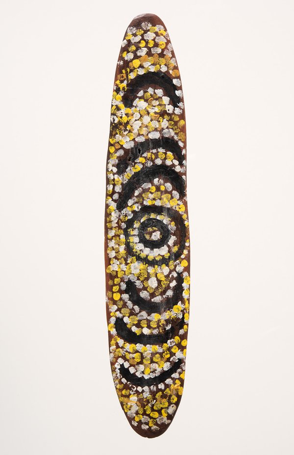 An oval wooden dance board painted with concentric circles and dense dot patterns in yellow.