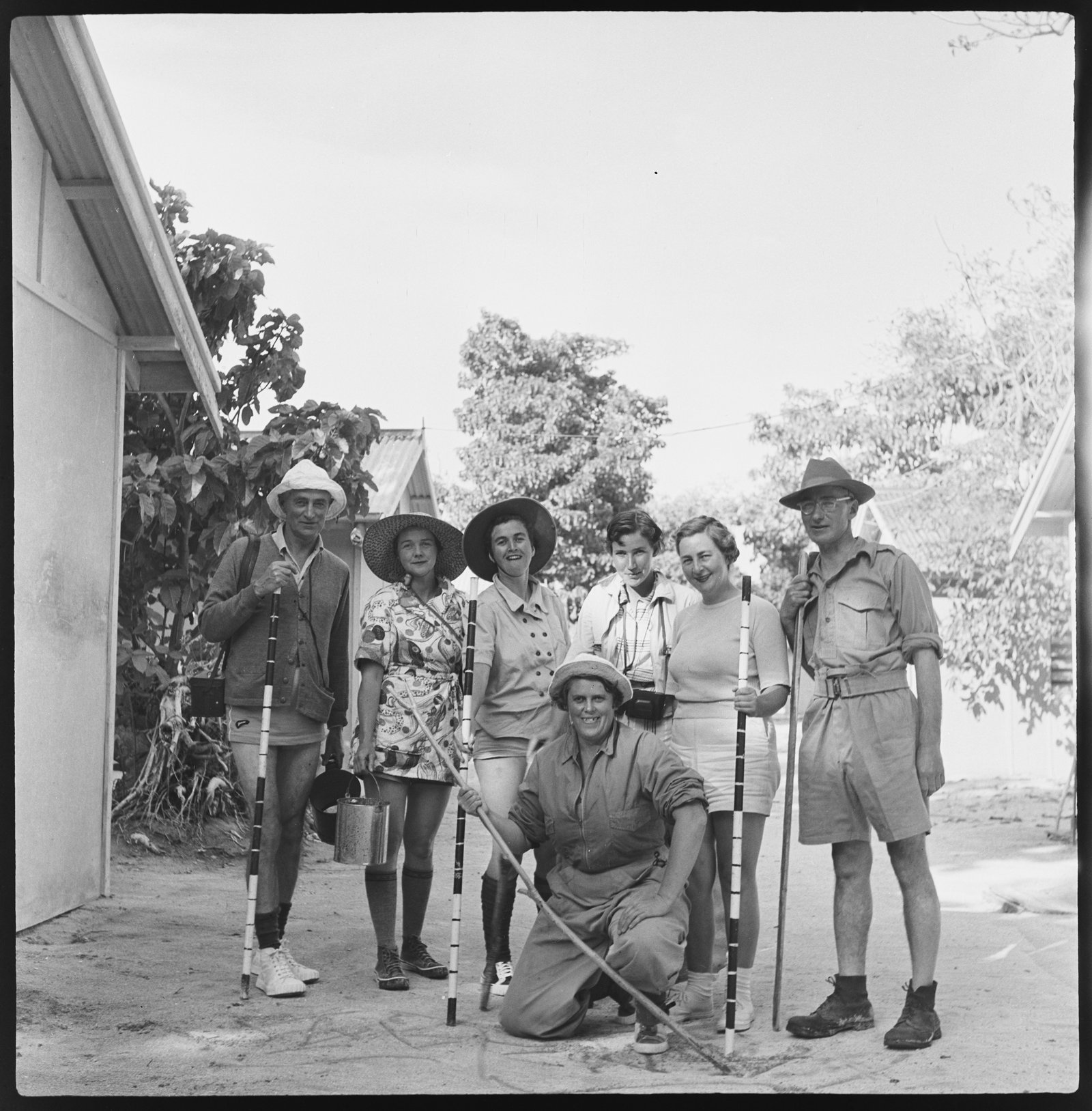 Black and white photograph of seven people with walking sticks.