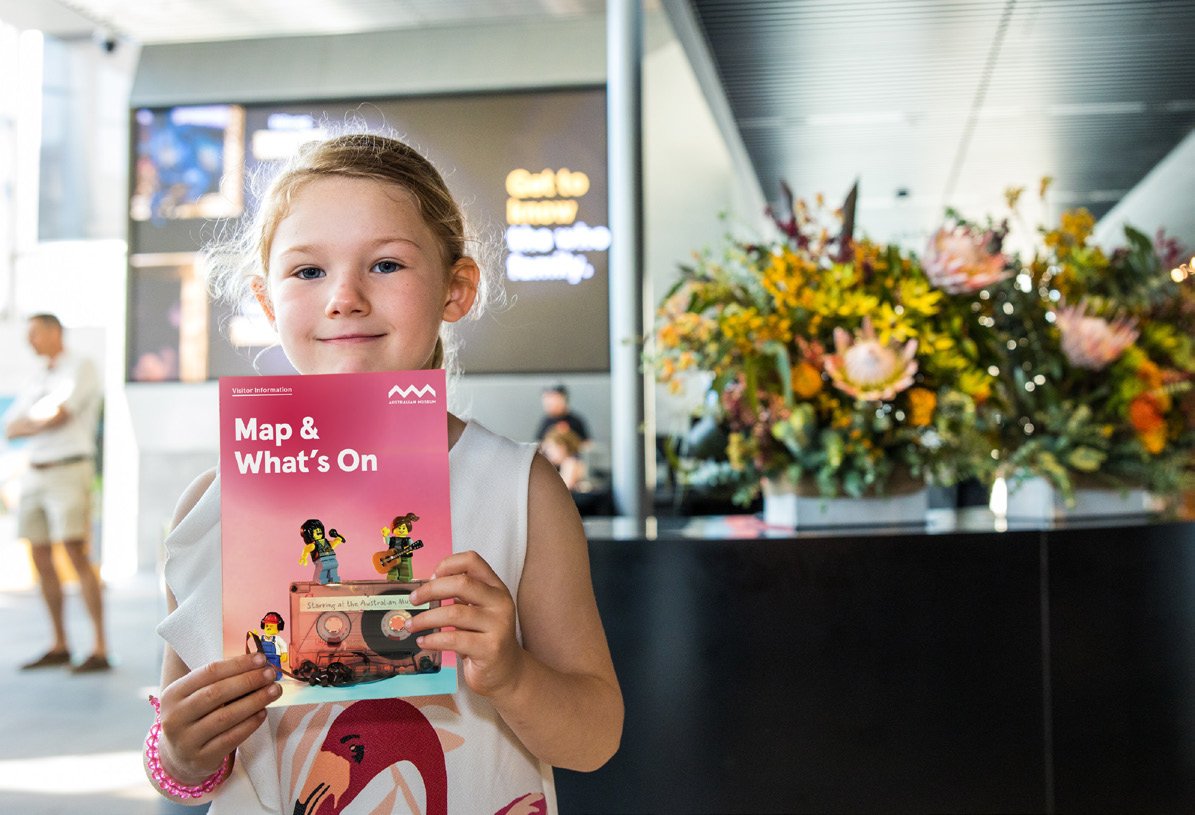 Child holding Australian Museum What's On calendar and map in Crystal Hall.