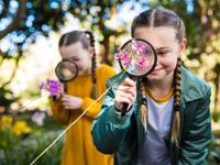 Two girls looking at flowers through magnifying glasses