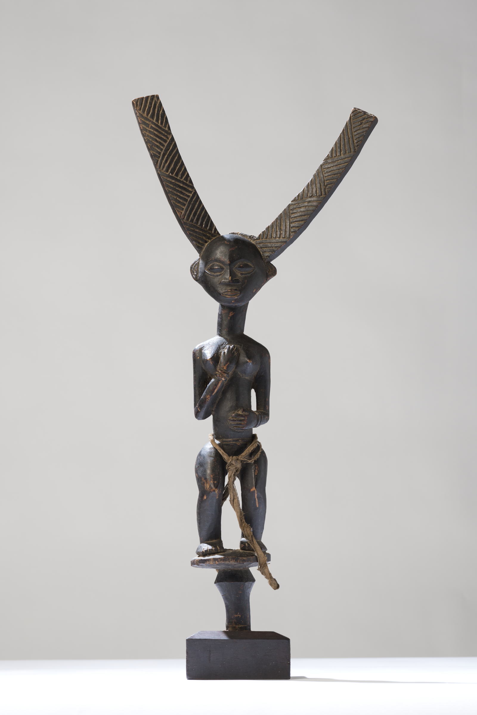 Carved wooden bow-stand featuring a female figure with a large Y-shaped fork, Luba people of Congo.