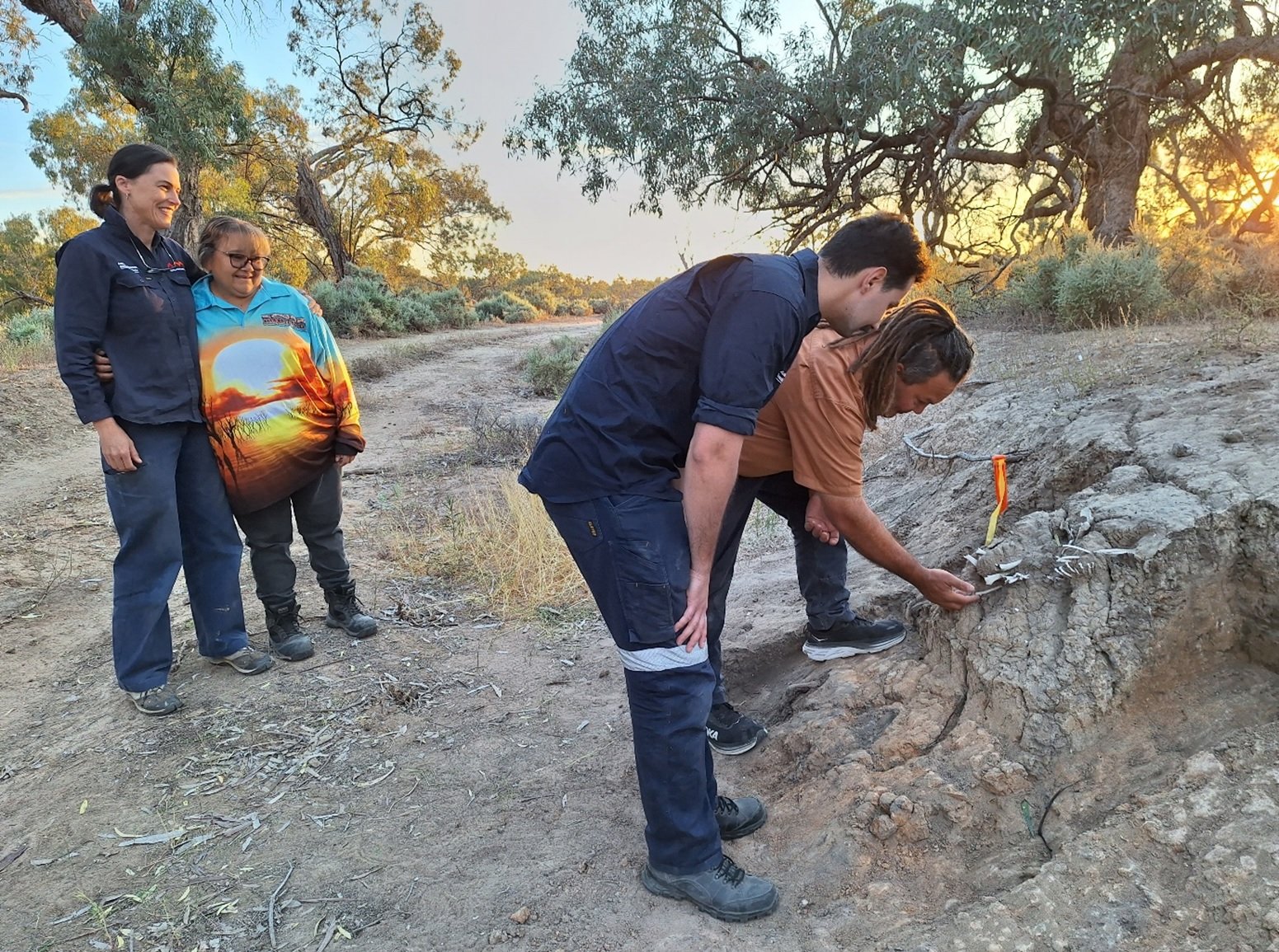 Researchers examine garli (dingo) bones protruding from a riverbank in Kinchega National Park.
