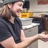 Scientist with a beanie and a beard is holding a tarantula in a lab.