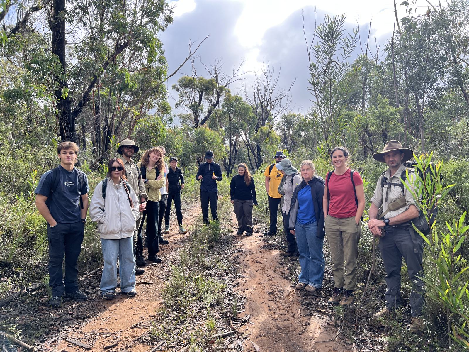 Fieldwork students and researchers on a bush track in the Blue Mountains before surveying potential rock shelter sites identified by drone mapping.