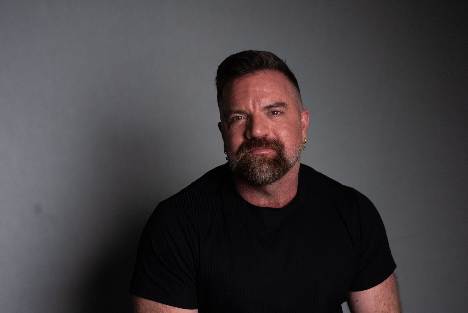 A closeup headshot of Leigh Boucher, against a grey wall.