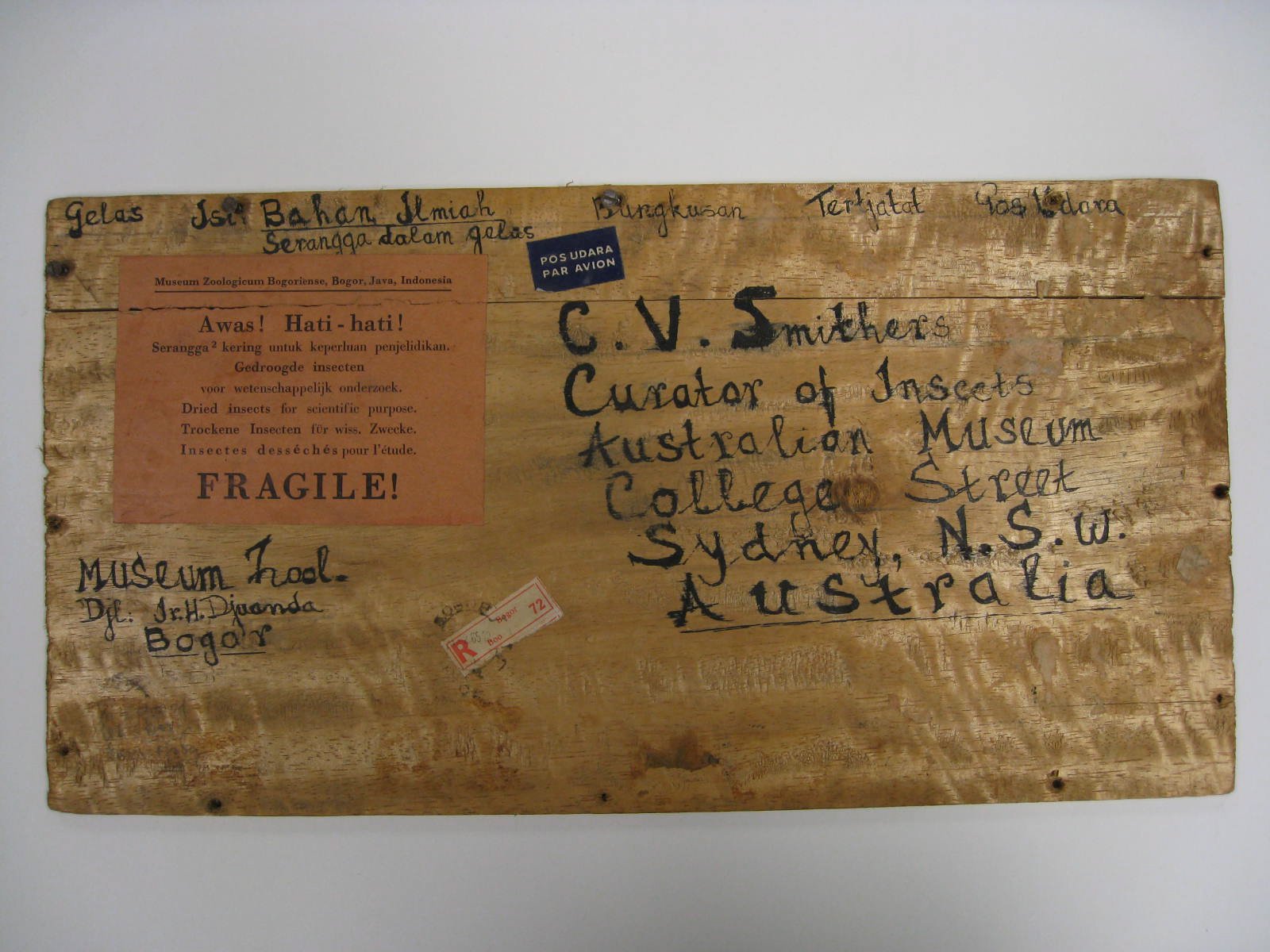 Photograph of a wooden box lid, with text listing the sender and receiver of the box.