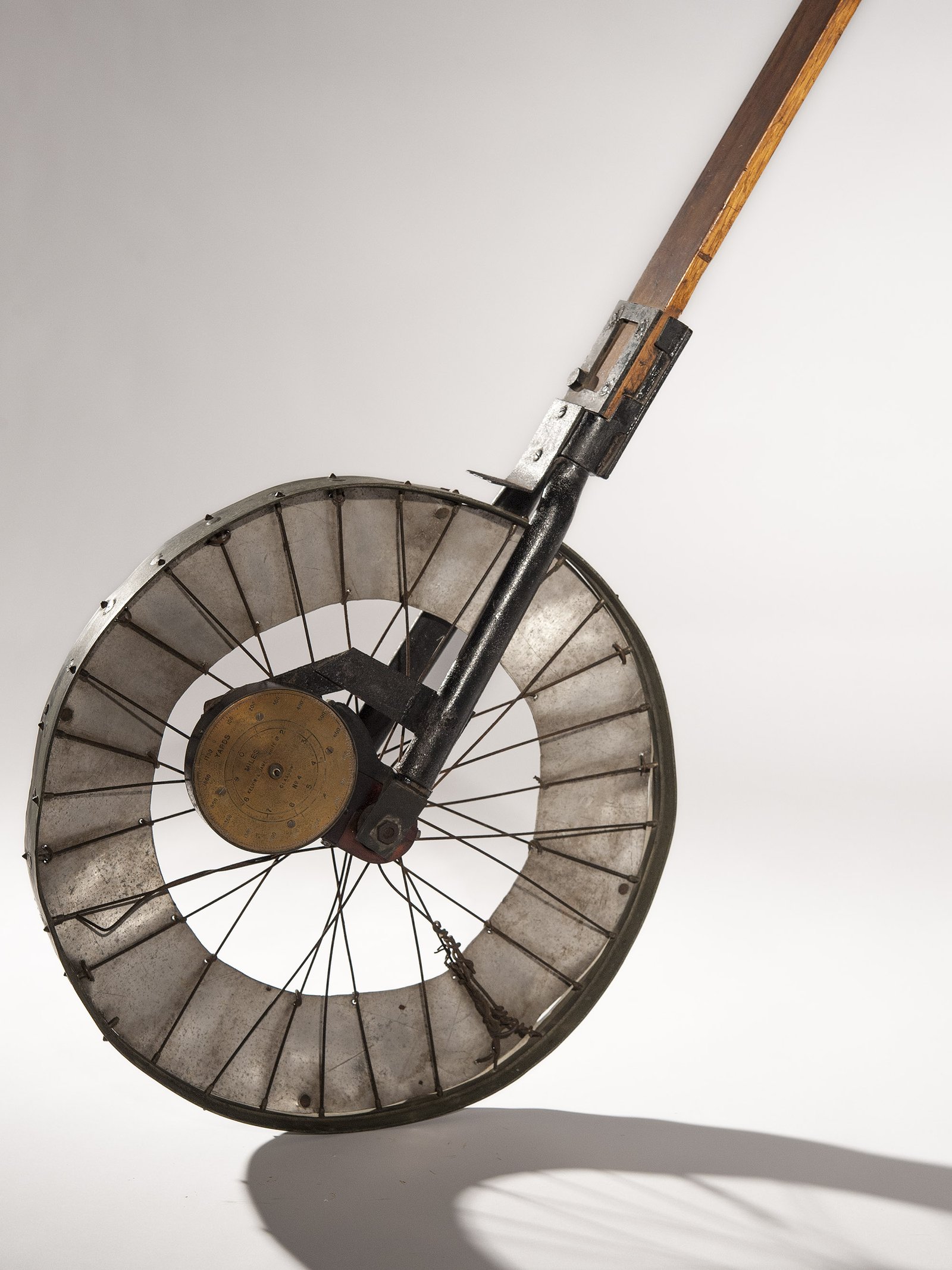 A large metal wheel on a long wooden handle, used to measure distance travelled across Antarctic ice