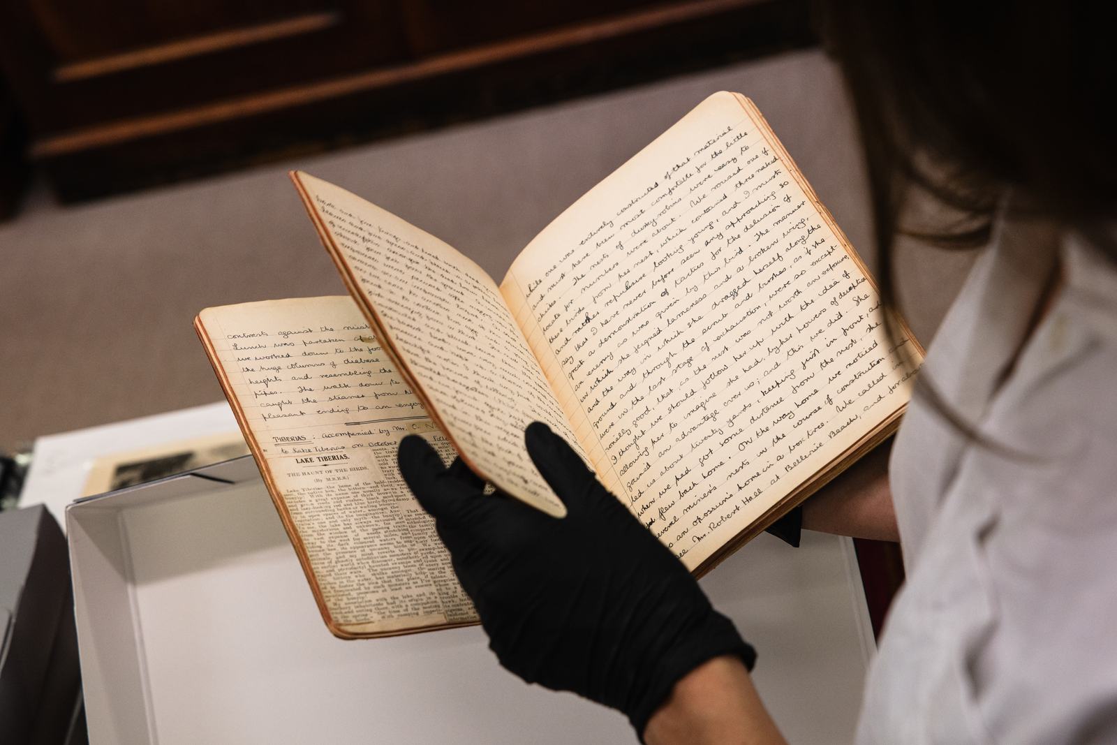 Photo of someone in a black glove holding a notebook.