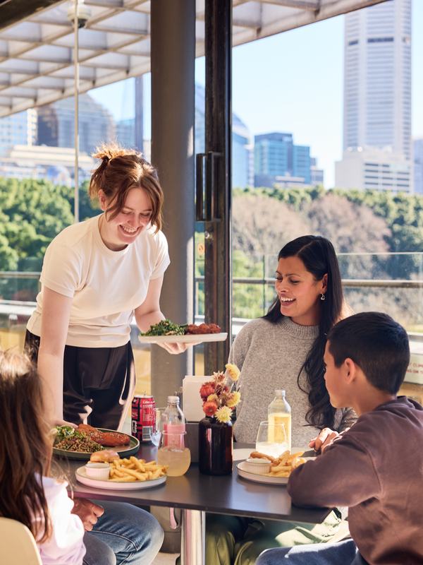 Visitors dining together at Bistro Gadi while food is served at their table.