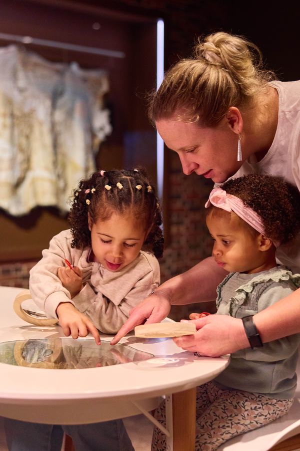 Woman and kids gathered around a tabletop activity.