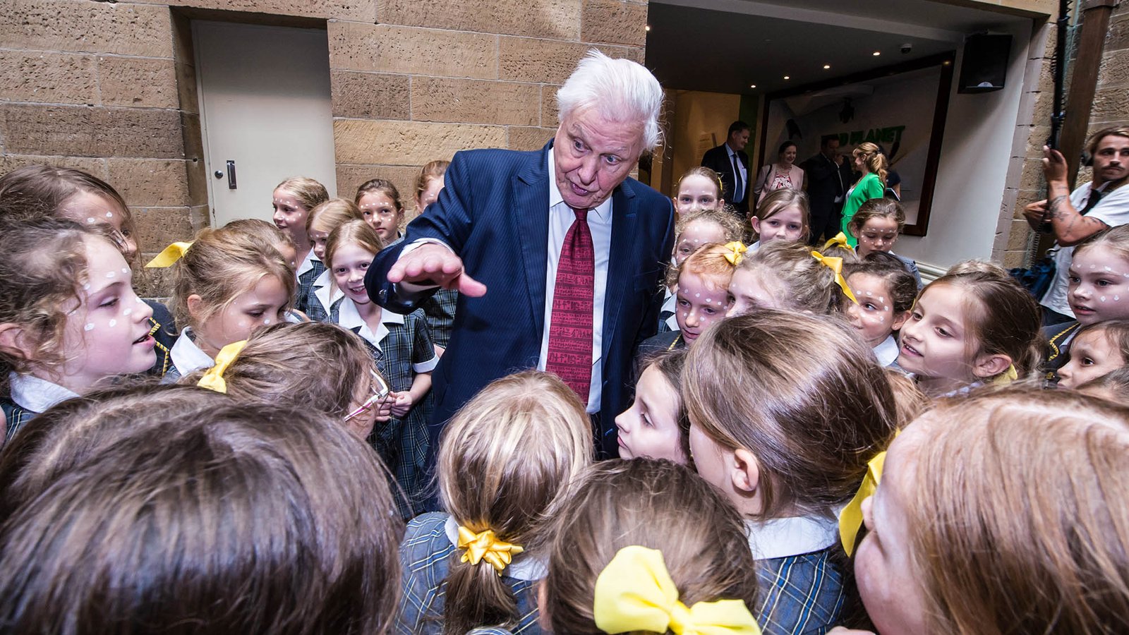 Sir David Attenborough surrounded by school children in Hintze Hall at the Australian Museum