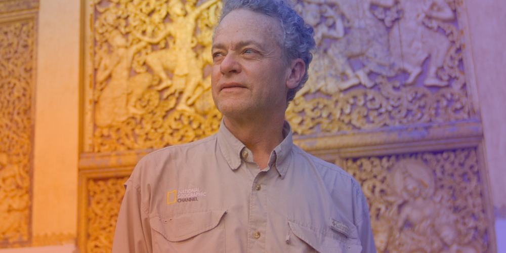 Terry Garcia stands before an ornate golden carved wall wearing a beige shirt