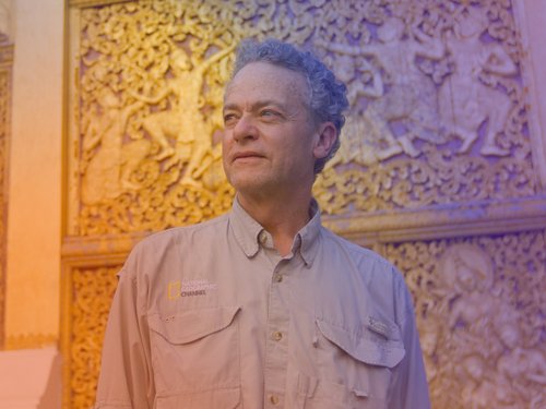 Terry Garcia stands before an ornate golden carved wall wearing a beige shirt