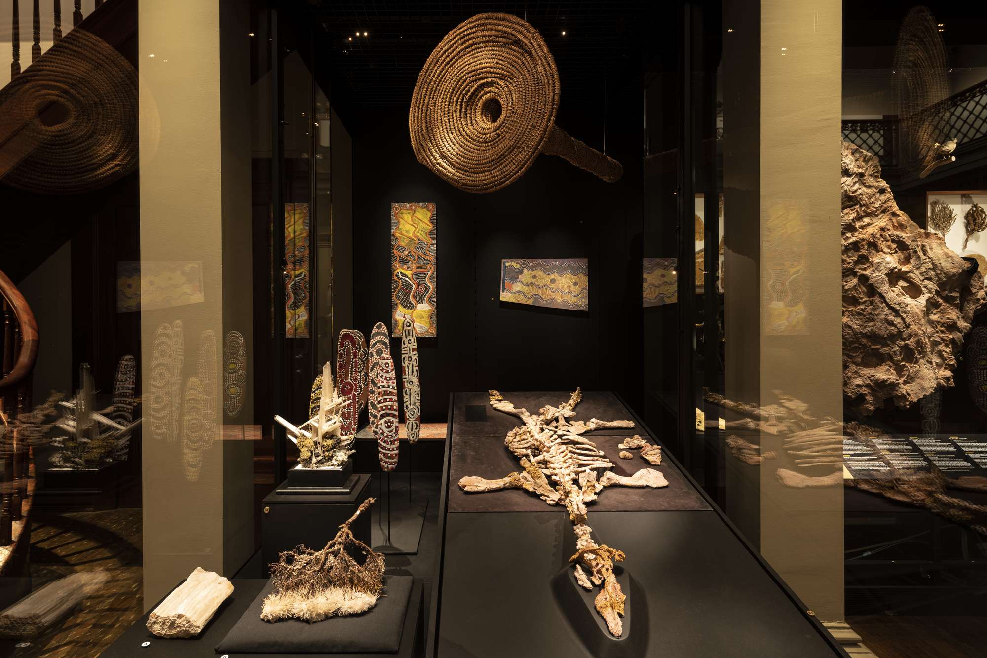 Museum gallery displaying a large opalised pliosaur skeleton and First Nations cultural objects.