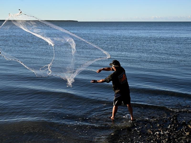 Fisherman casts a net into the water in Cairns, Queensand