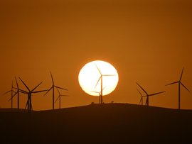 The sun rises over power-generating wind turbines