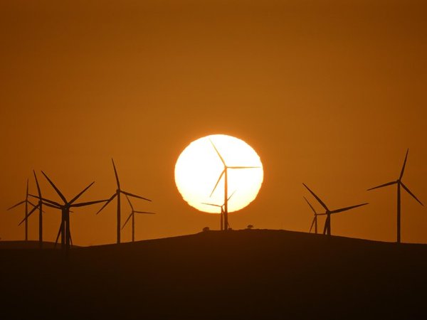 The sun rises over power-generating wind turbines