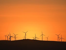 The sun rises over power-generating wind turbines