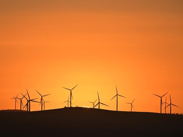 The sun rises over power-generating wind turbines