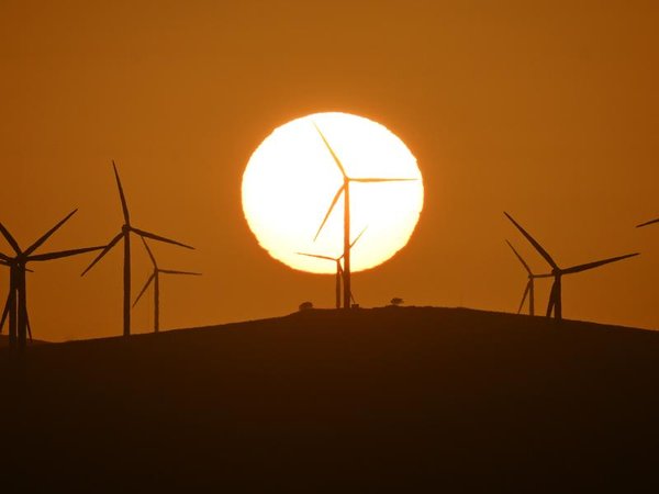 The sun rises over power-generating wind turbines