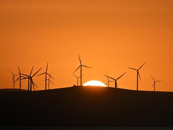 The sun rises over power-generating wind turbines