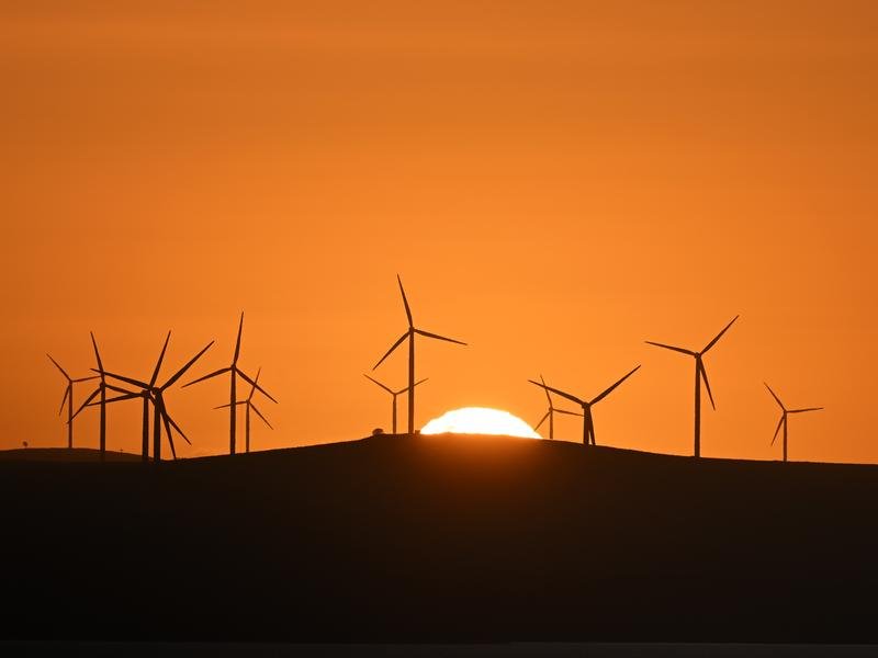 The sun rises over power-generating wind turbines