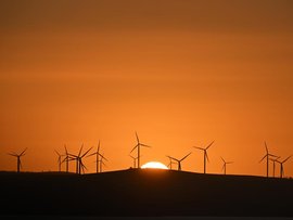 The sun rises over power-generating wind turbines