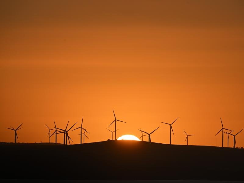 The sun rises over power-generating wind turbines